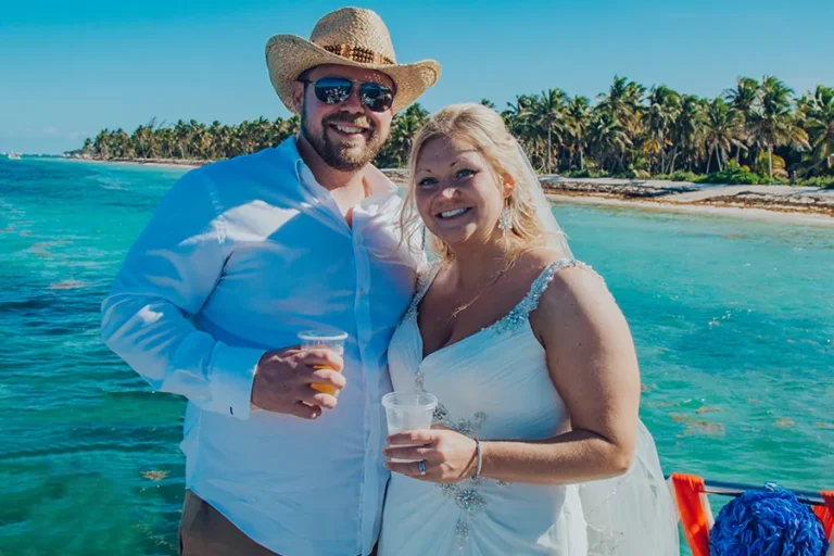 Newlyweds toasting in the shallow water beside the catamaran