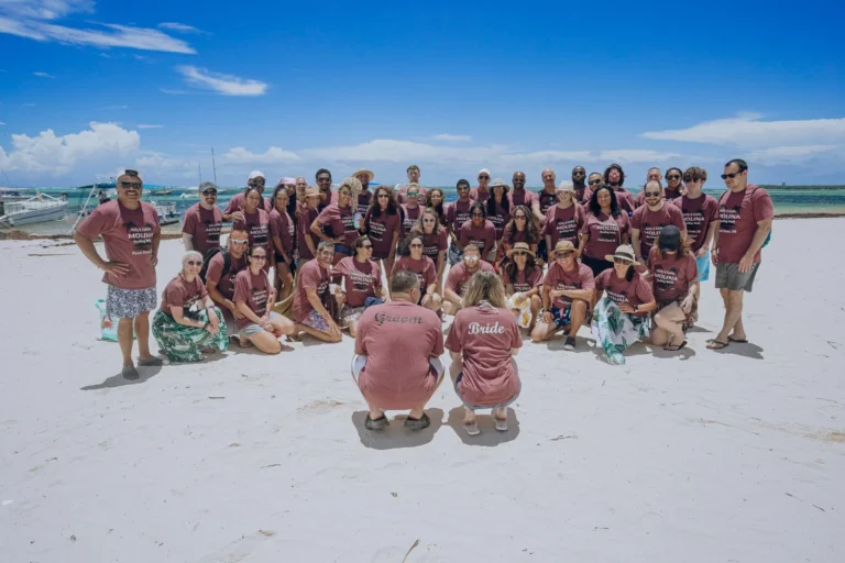 The whole wedding group photographed on the beach stop