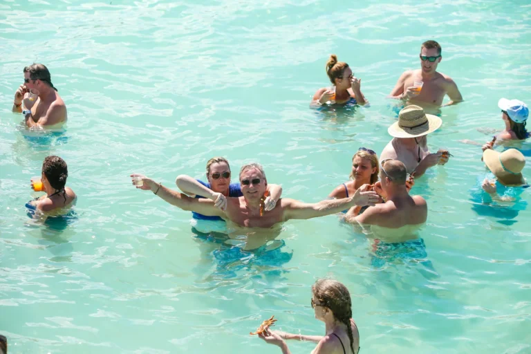 Guests relaxing in the natural pool with drinks in hand