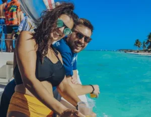 A couple in the shallow turquoise water beside the boat