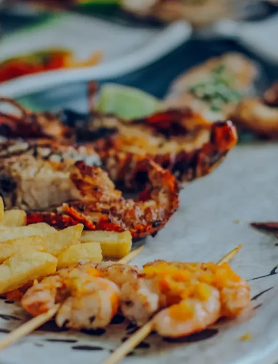 Grilled lobster with fries, shrimp skewers and calamari, plated on board